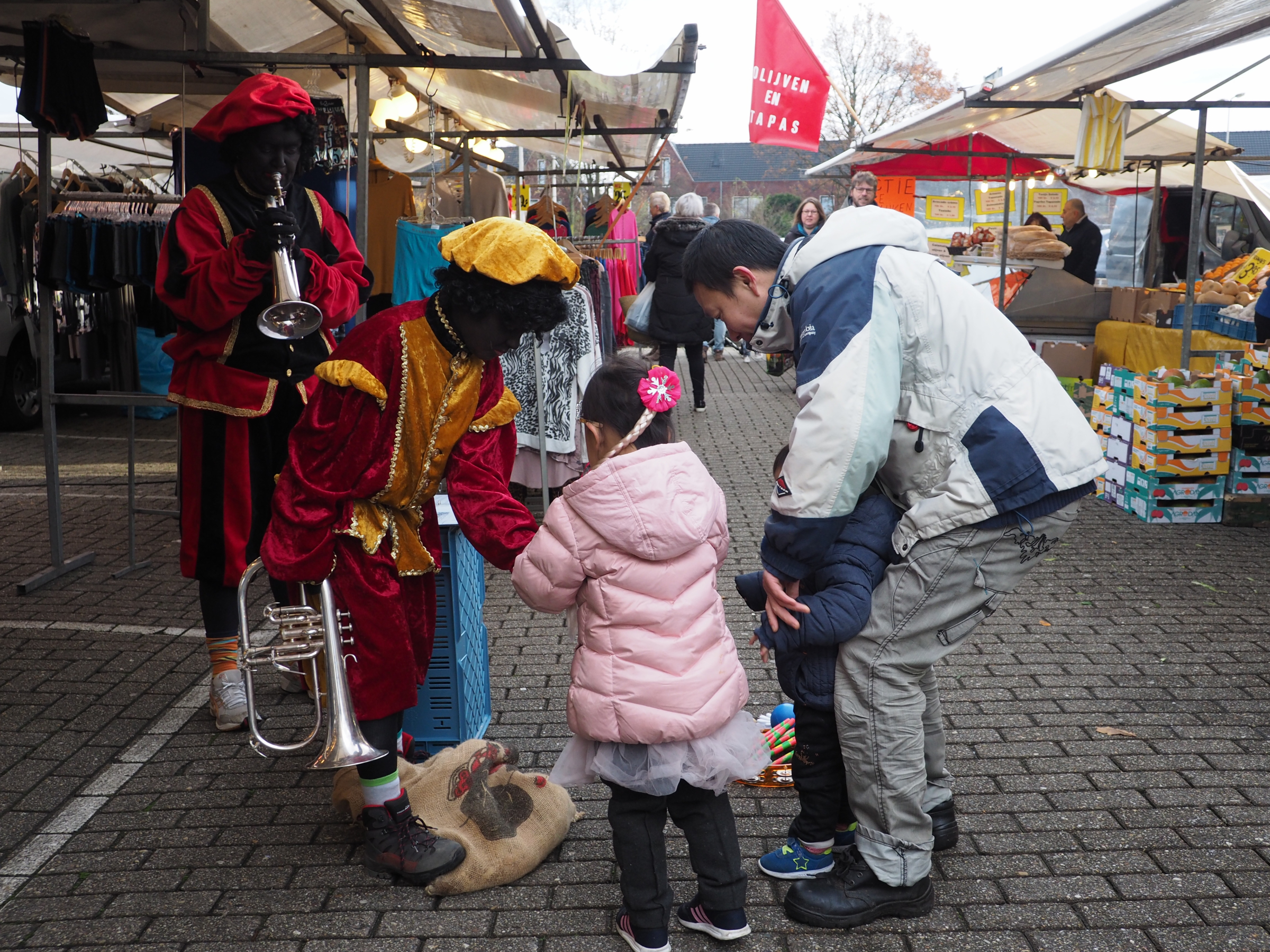 Two zwarte pieten giving out candy to children.